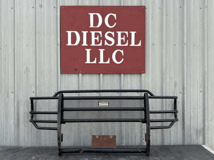 99-04 Ford F250 F350 Front Ranch Hand Grill Brush Guard in used condition with light wear and a bent lower pipe, displayed against a corrugated metal wall beneath a DC Diesel LLC sign, compatible with 1999-2004 Ford Super Duty models including 6.0L Powerstroke engines.