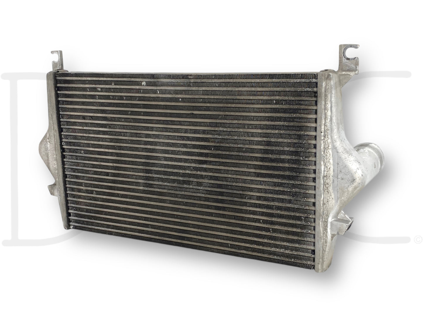 Used OE 99-02 Ford F250 F350 7.3 7.3L Powerstroke Diesel Intercooler Charge Air Cooler with light wear, compatible with 1999-2002 Ford Excursion, F-250, F-350, F-450, and F-550 trucks, showing the cooling fins and inlet/outlet pipes.